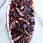 beet and fennel salad on an oval tray with a gold and silver serving spoon