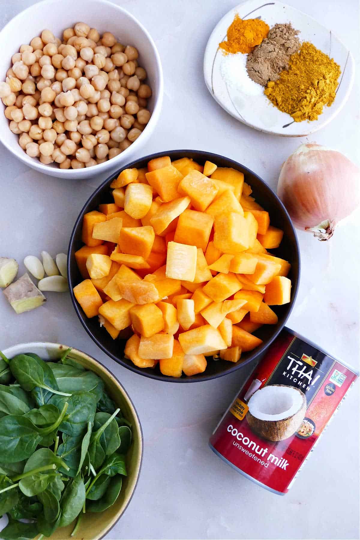chickpeas, butternut squash, onion, garlic, spinach, coconut milk, and seasonings on a counter
