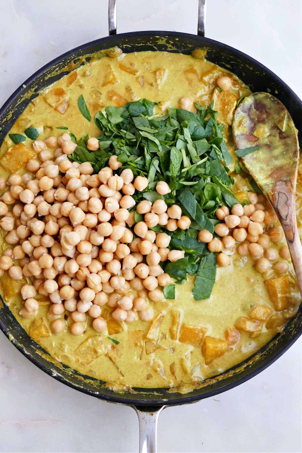 butternut squash and chickpea curry simmering in a large skillet on a counter