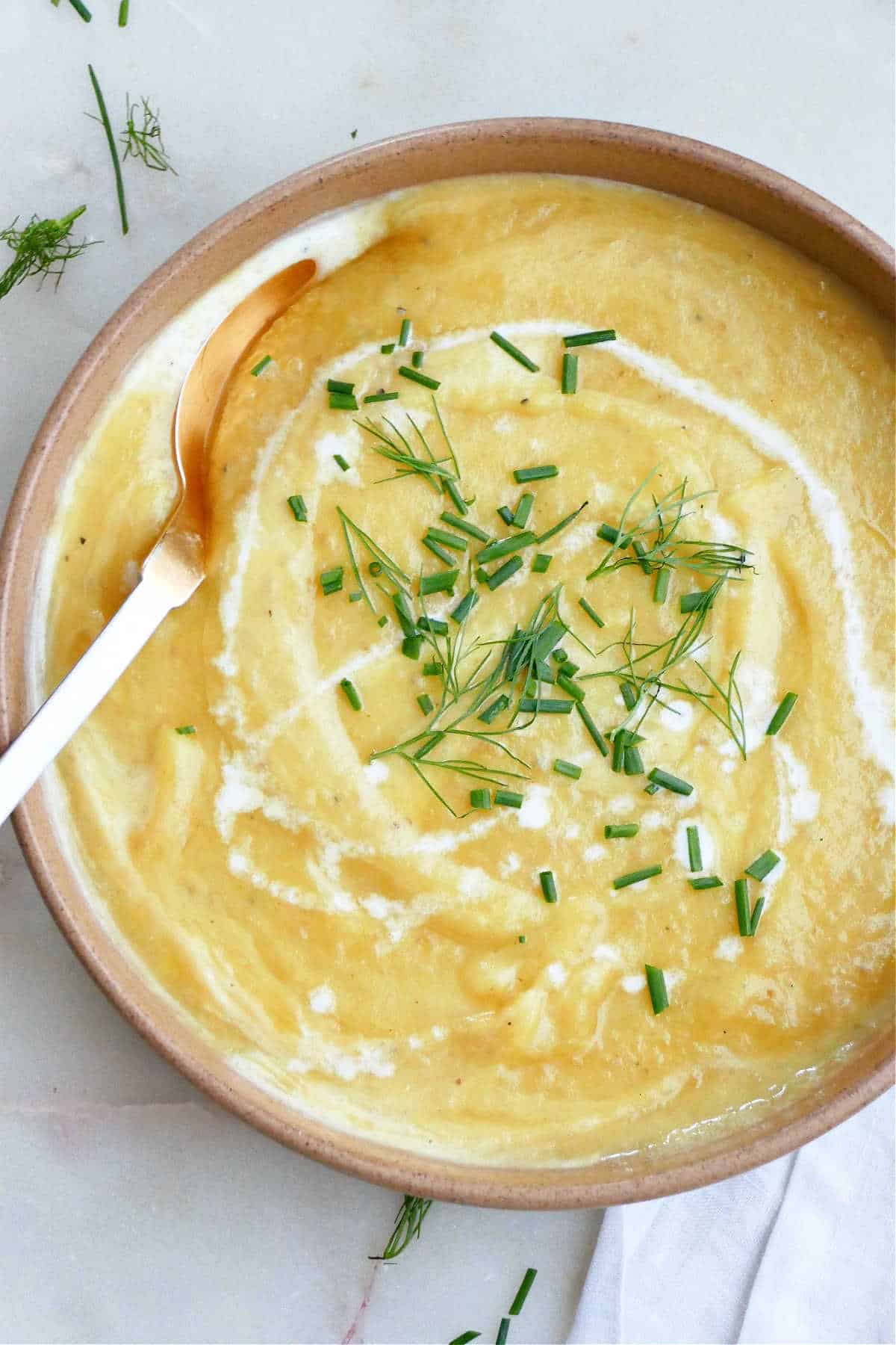 potato leek soup with fennel topped with chives and cream in a bowl with a spoon