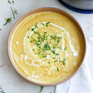 leek, potato, and fennel soup in a bowl with chives and heavy cream