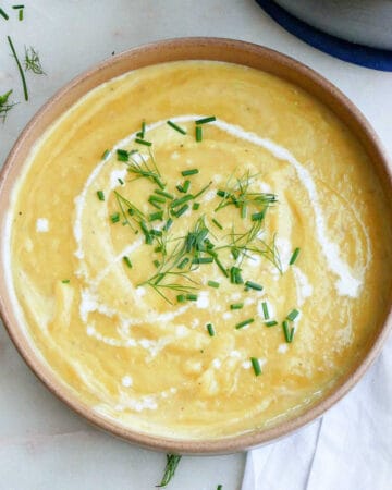 leek, potato, and fennel soup in a bowl with chives and heavy cream