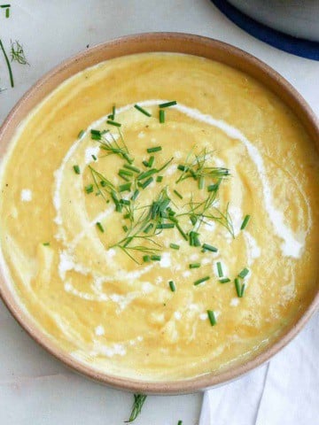 leek, potato, and fennel soup in a bowl with chives and heavy cream