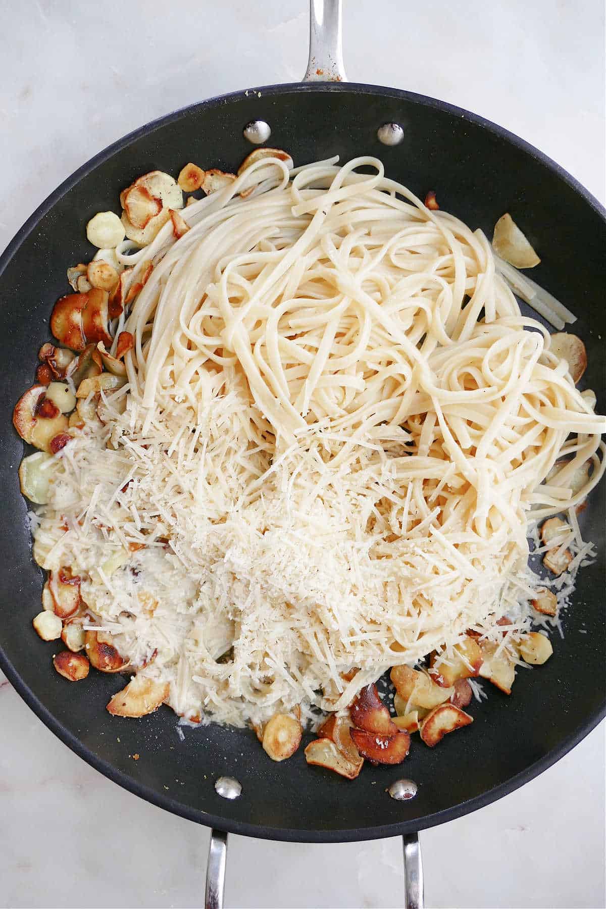sauteed parsnips, pasta, and parmesan cheese cooking in a large skillet