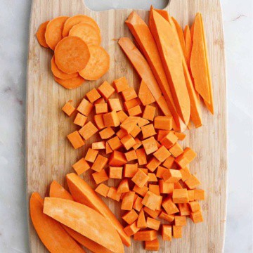 sweet potatoes cut into different shapes on a bamboo cutting board on a counter