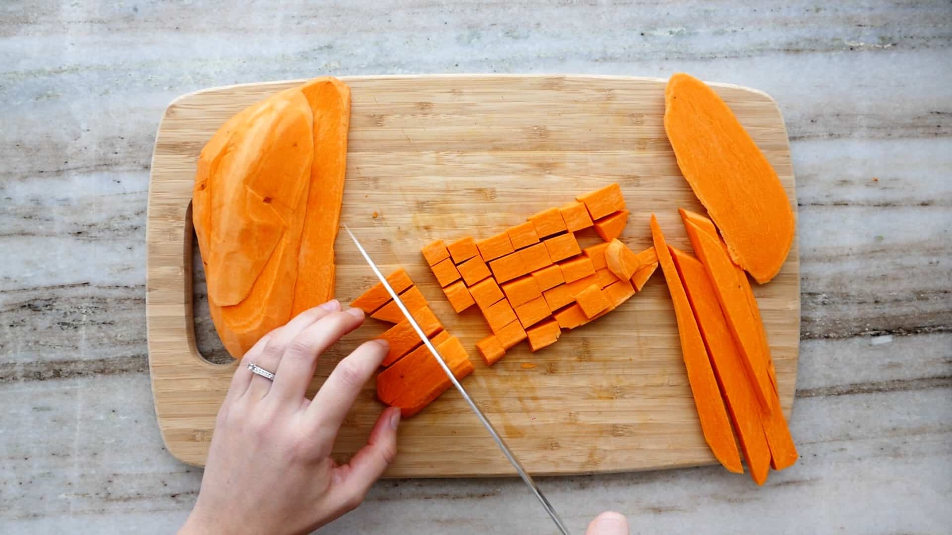 woman cutting sweet potatoes into cubes with a knife