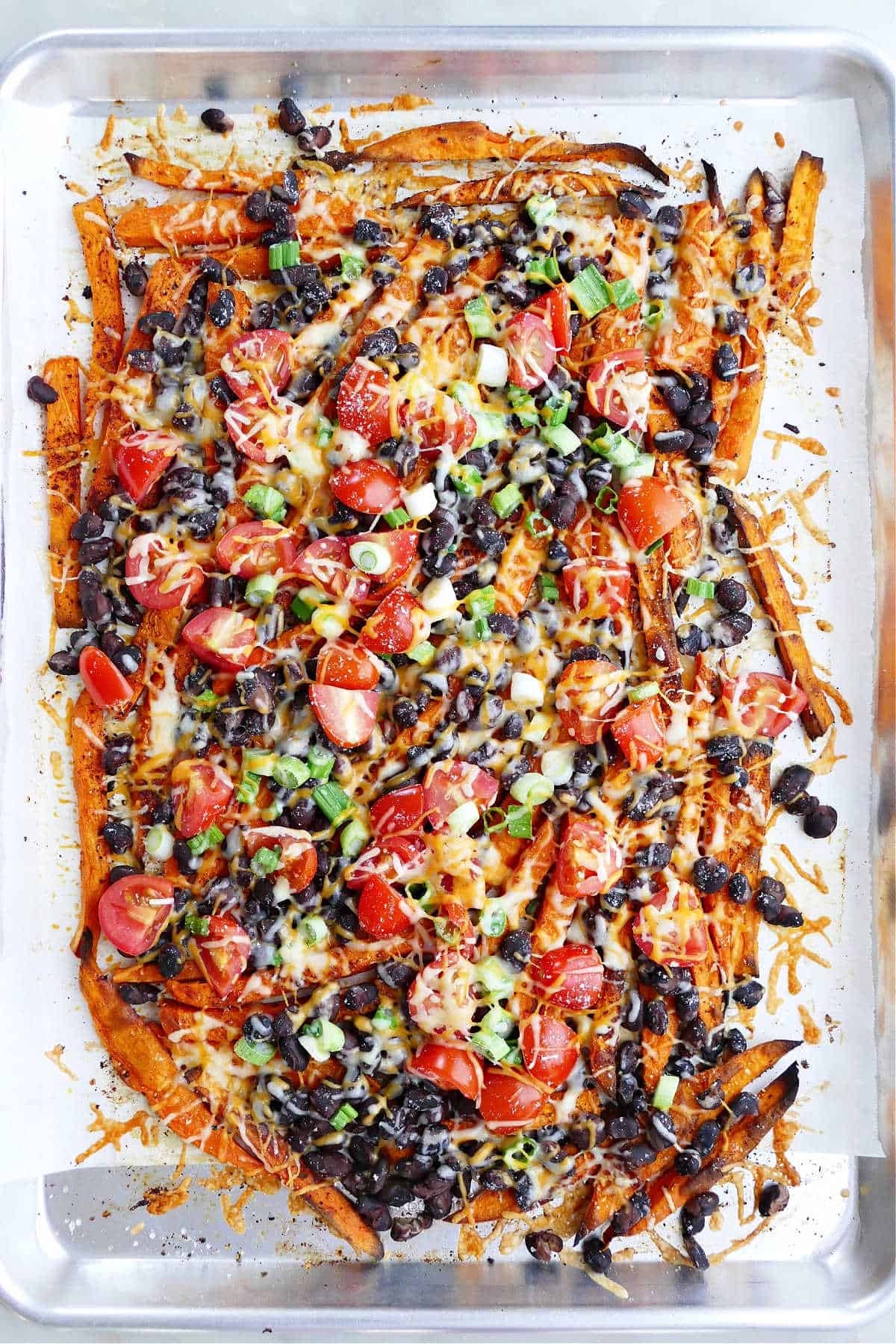 loaded sweet potato fries on a baking sheet lined with parchment paper