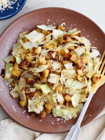 fried cabbage and potatoes on a serving plate next to a fork