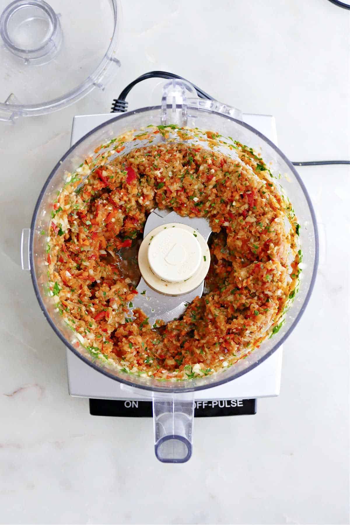 finely chopped vegetables and herbs in a food processor on a counter
