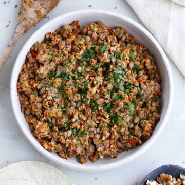 vegan lentil walnut taco meat in a serving dish next to a spoon and napkin