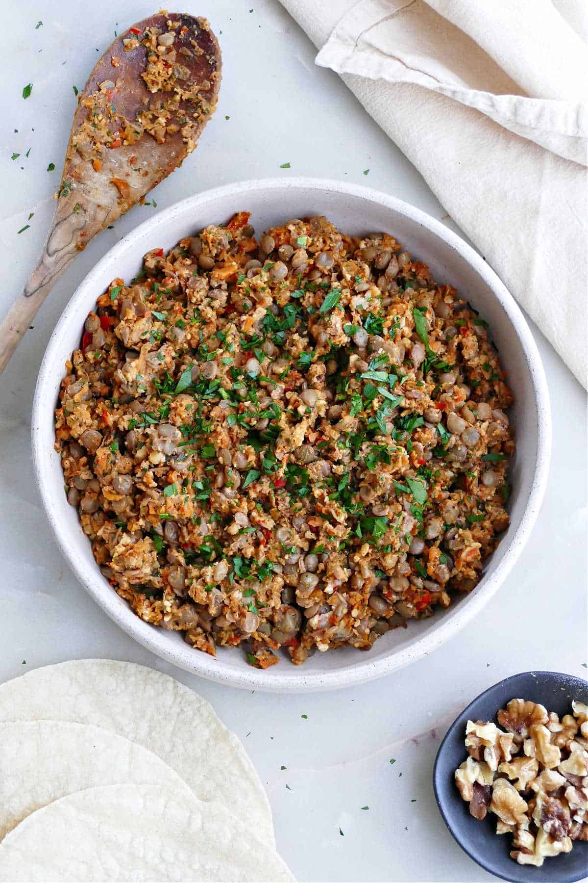 vegan lentil walnut taco meat in a serving dish next to a spoon and napkin