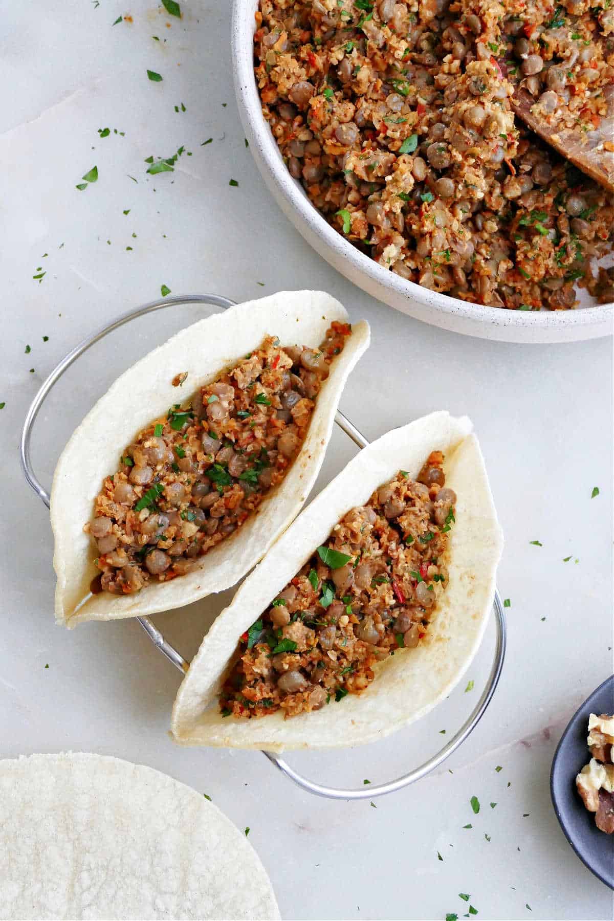 two corn tortillas filled with lentil walnut taco meat in a taco holder