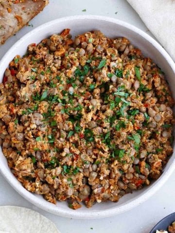 vegan lentil walnut taco meat in a serving dish next to a spoon and napkin