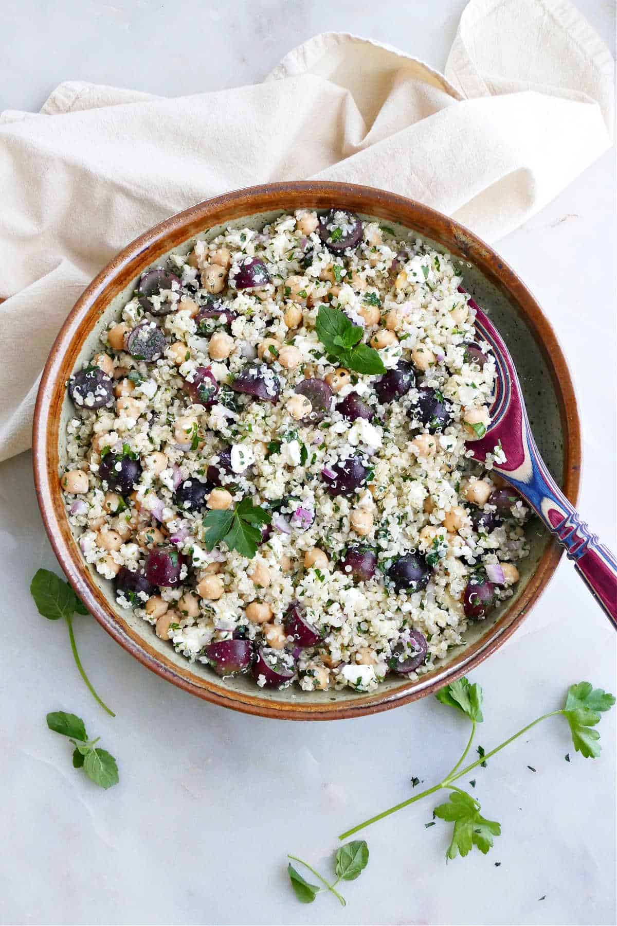 quinoa grape salad with herbs in a serving bowl with a spoon