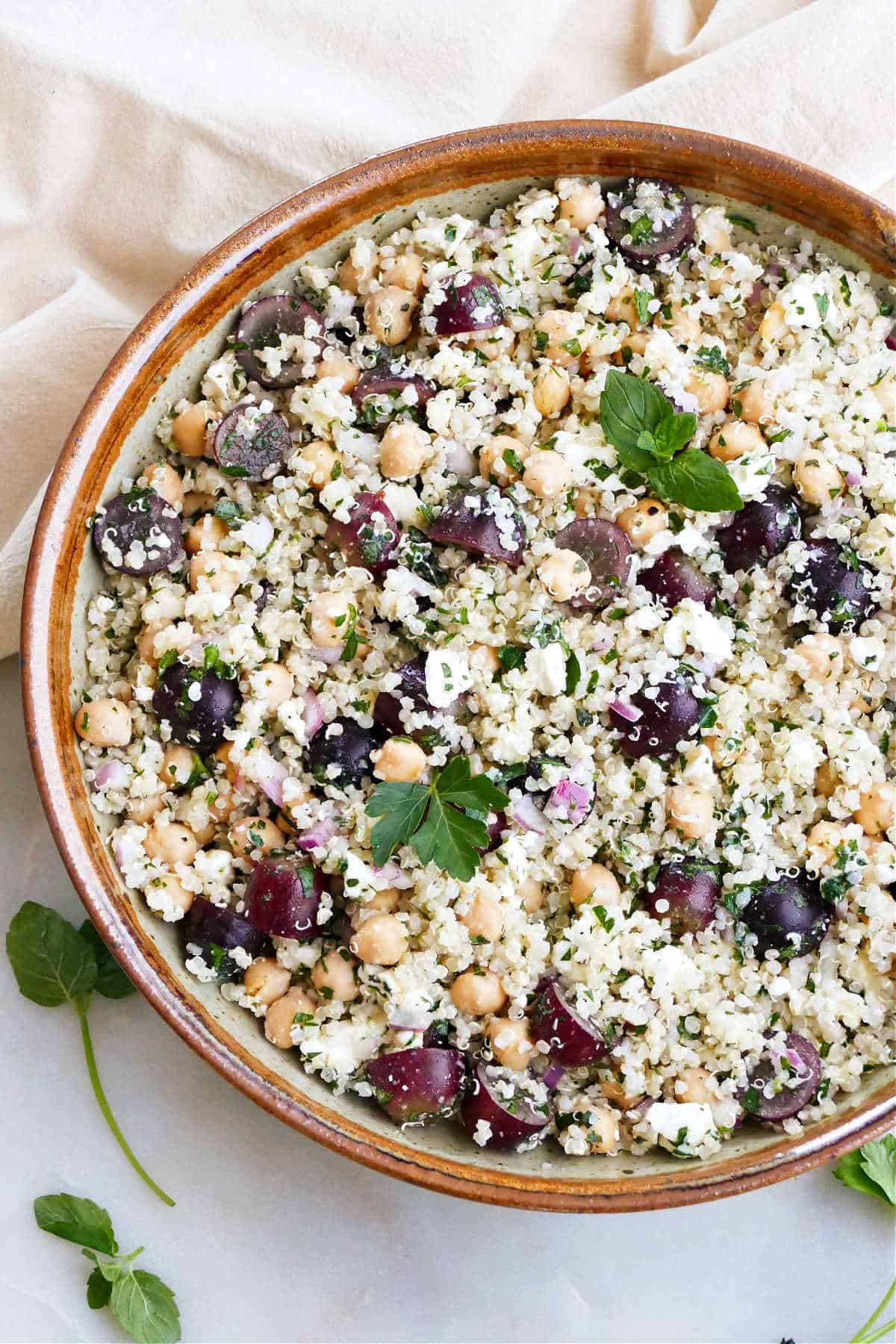 quinoa grape salad with tabouleh in a large brown serving bowl on a counter