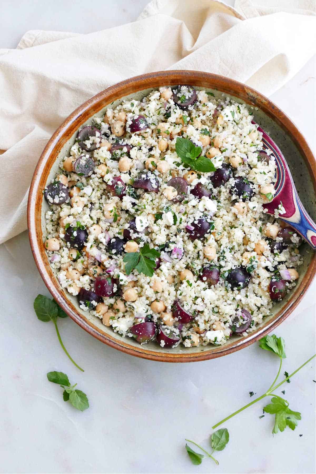 quinoa grape salad with herbs in a serving bowl with a spoon