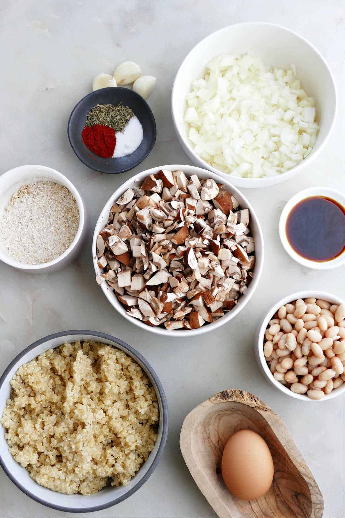 spices, onion, soy sauce, beans, mushrooms, oats, quinoa, and egg on a counter