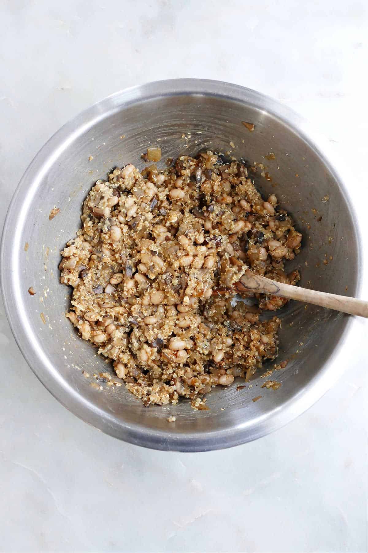 batter for quinoa mushroom burgers in a mixing bowl with a wooden spoon