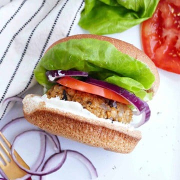 quinoa mushroom burger topped with lettuce, onion, and tomato on a bun