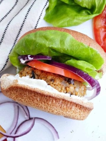 quinoa mushroom burger topped with lettuce, onion, and tomato on a bun