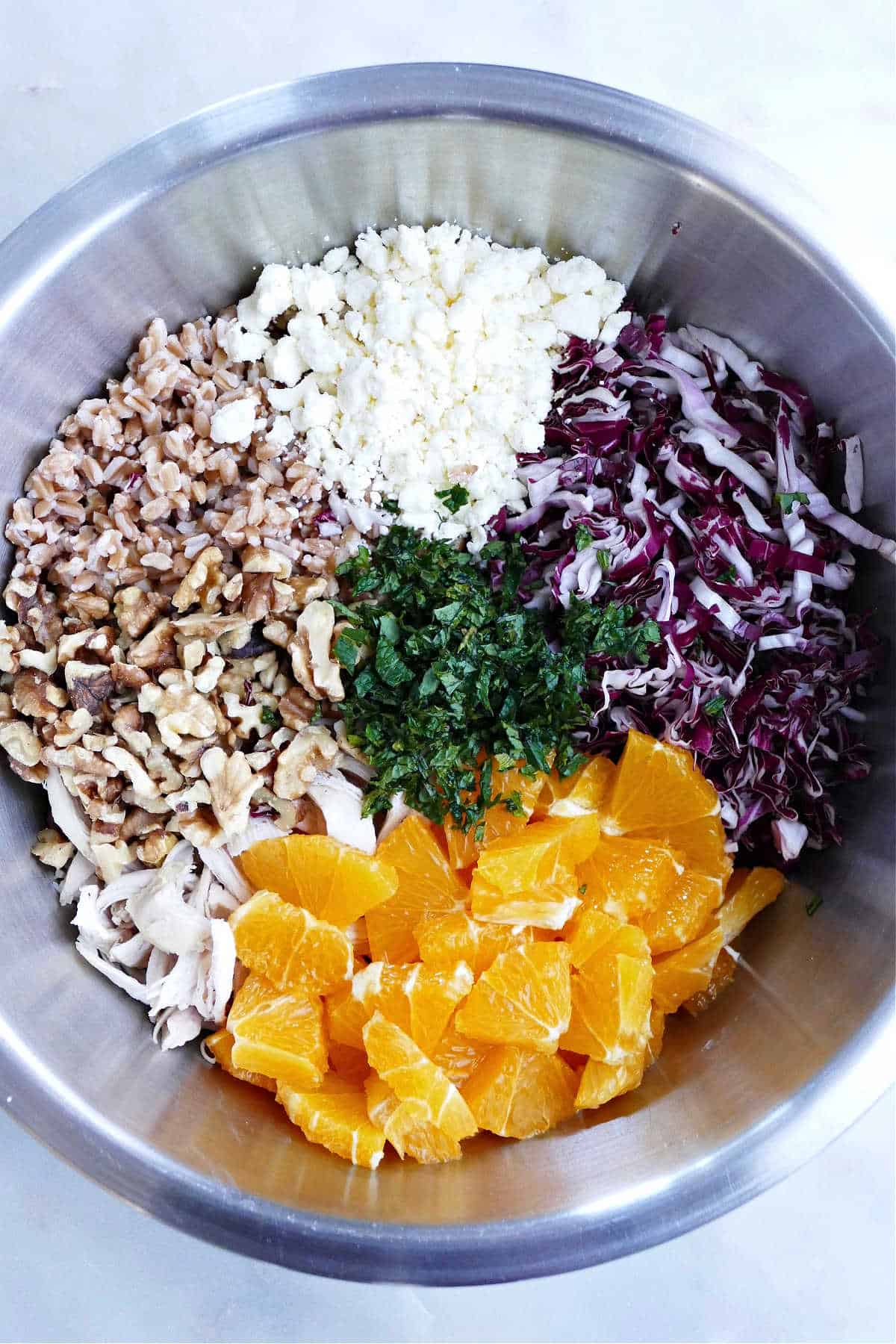 ingredients for shredded radicchio salad with chicken and farro in a mixing bowl on a counter