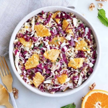 radicchio salad with oranges, chicken, farro, and herbs in a serving bowl on a counter