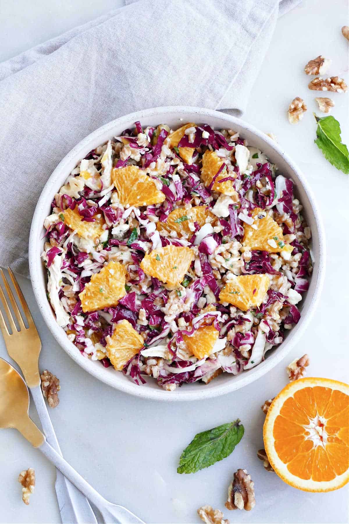 radicchio salad with oranges, chicken, farro, and herbs in a serving bowl on a counter