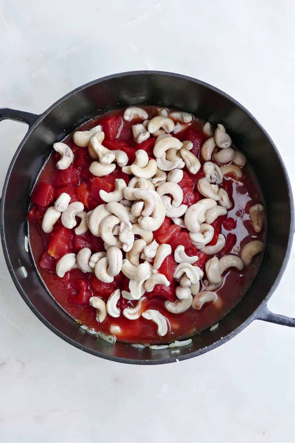 diced tomatoes, onion, garlic, and soaked cashews cooking a large soup pot