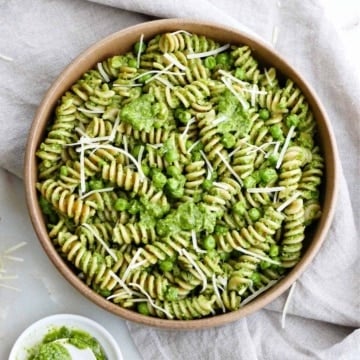 vegetarian pesto pasta in a serving bowl on a napkin next to pesto