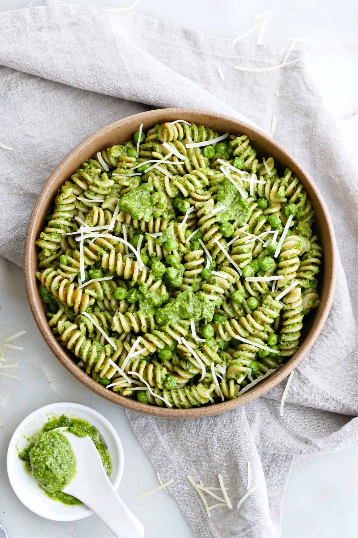 vegetarian pesto pasta in a serving bowl on a napkin next to pesto