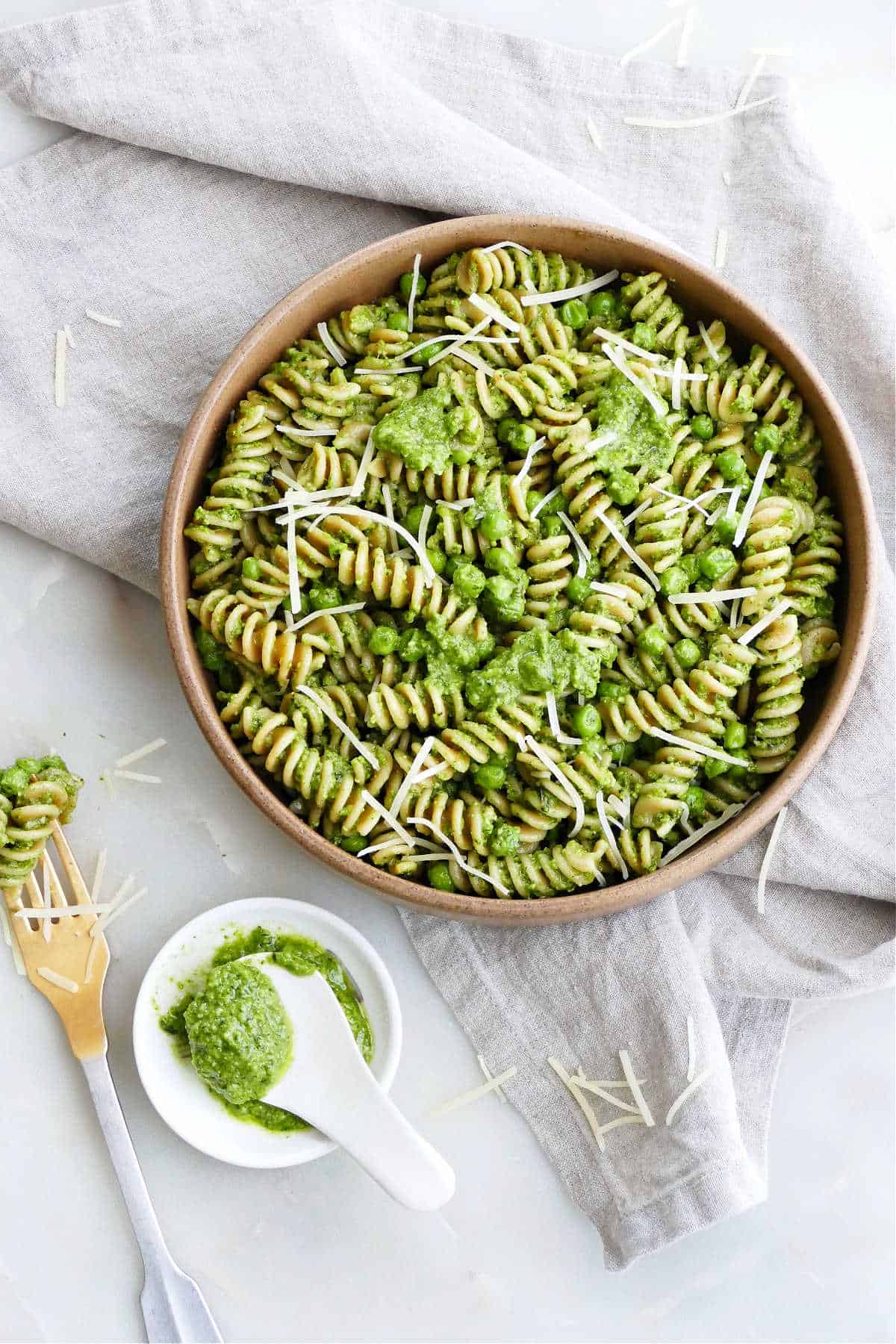 vegetarian pesto pasta with peas in a bowl on a napkin next to pesto