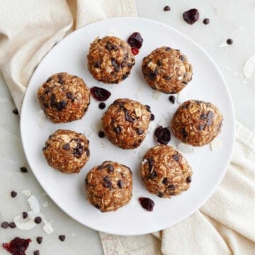 eight almond butter energy balls with cherries on a serving plate on a napkin