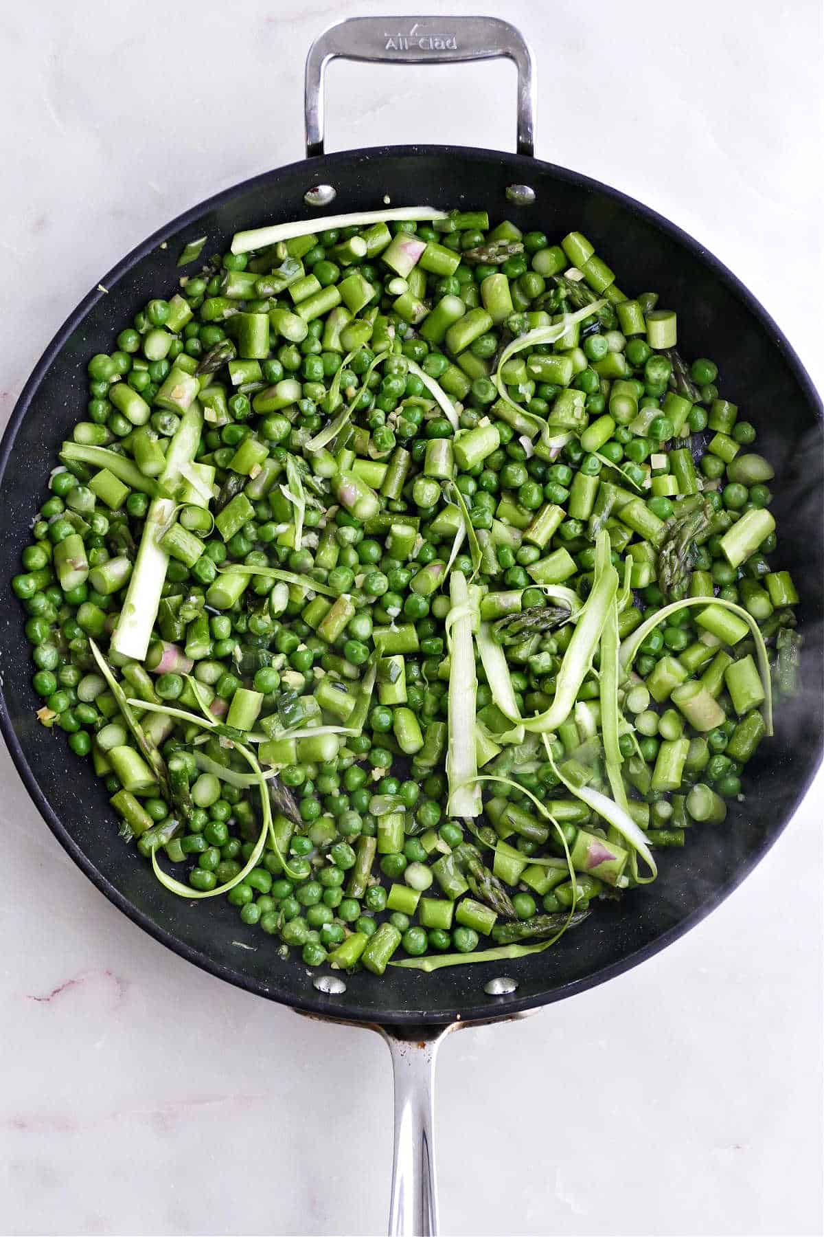 asparagus, peas, green onions, and ginger cooking in a nonstick skillet