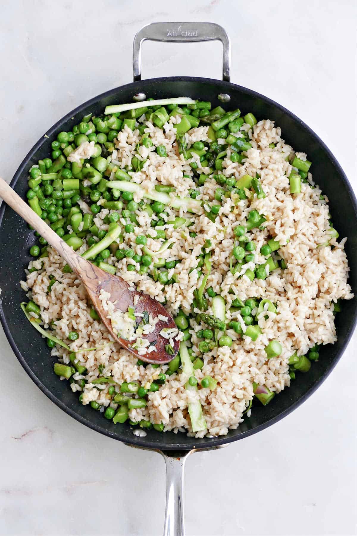 asparagus, peas, green onions, and brown rice cooking in a nonstick skillet