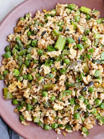 asparagus fried rice on a serving plate with chopsticks next to toppings