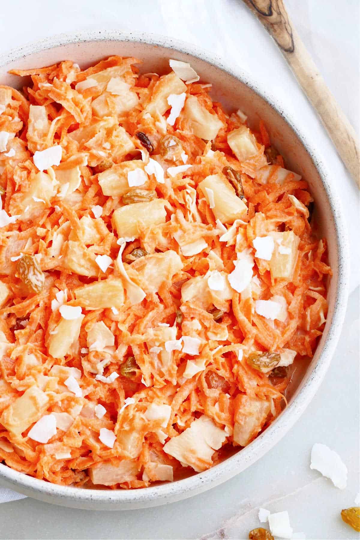 carrot, pineapple, raisin, and coconut salad in a serving bowl on a counter