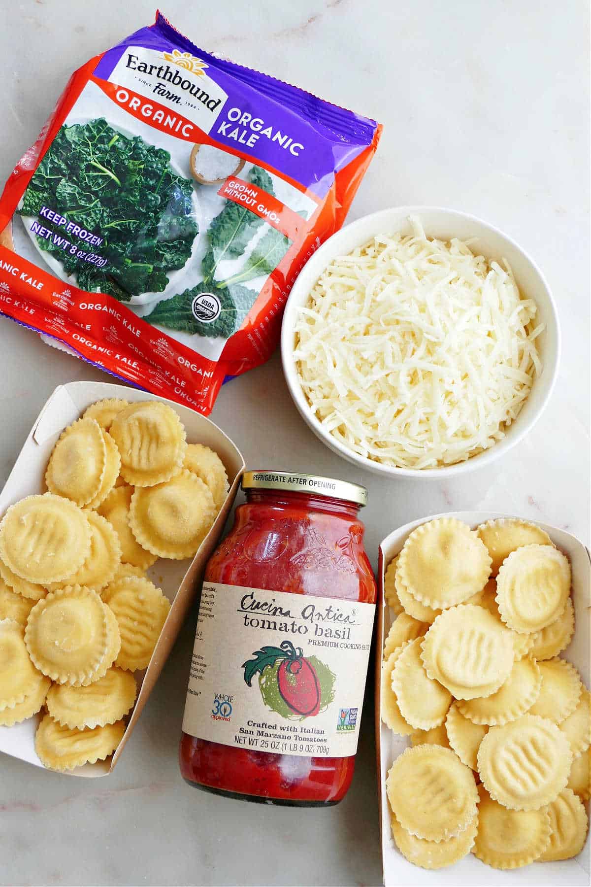 frozen kale, shredded mozzarella, marinara sauce, and ravioli on a counter