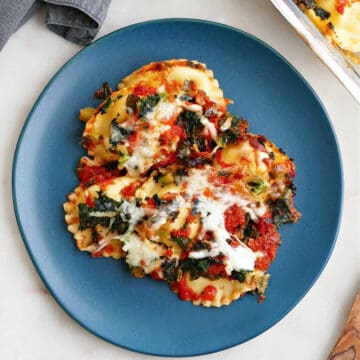 baked ravioli casserole with kale on a serving dish on a counter