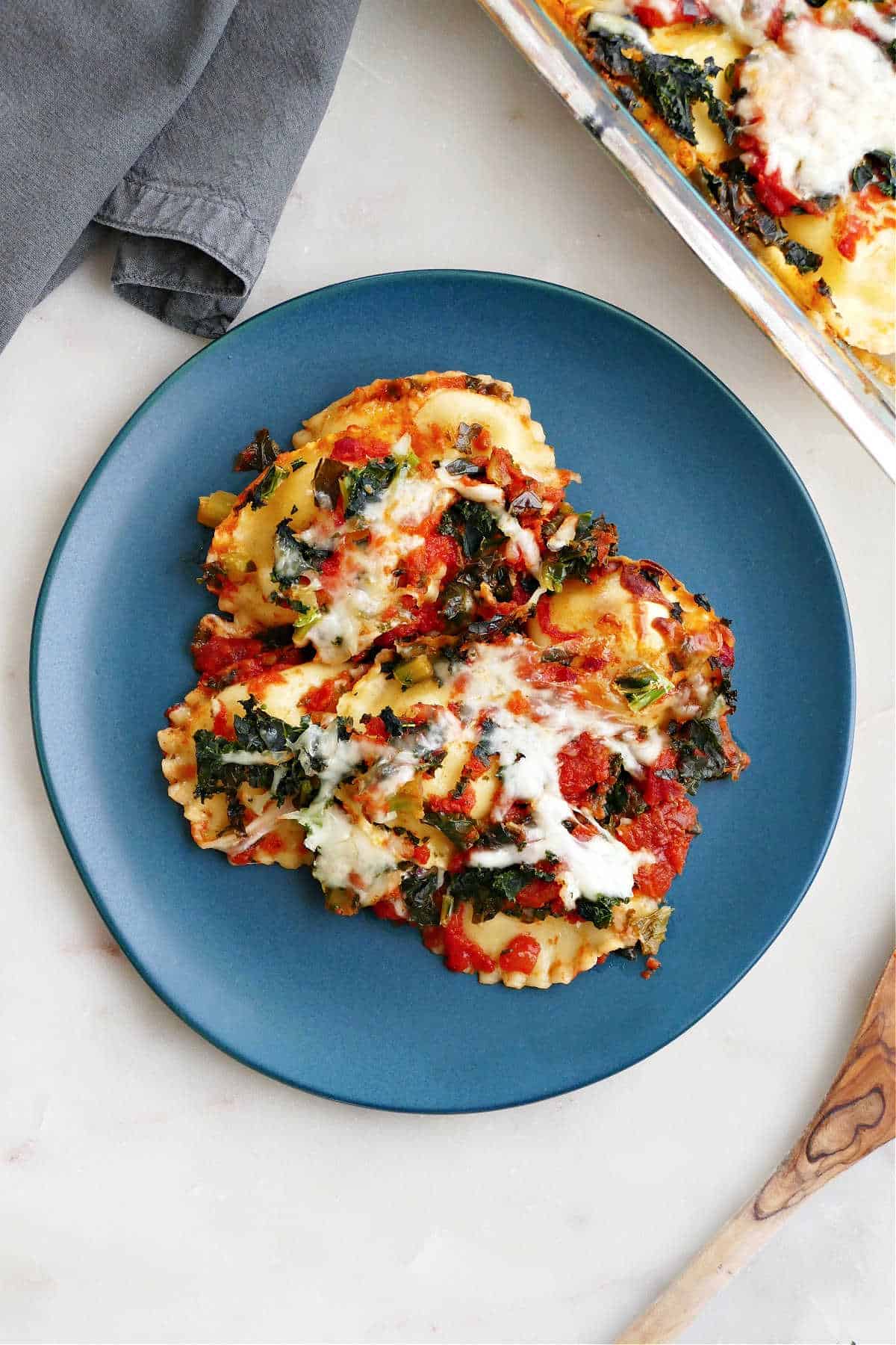 baked ravioli casserole with kale on a serving dish on a counter