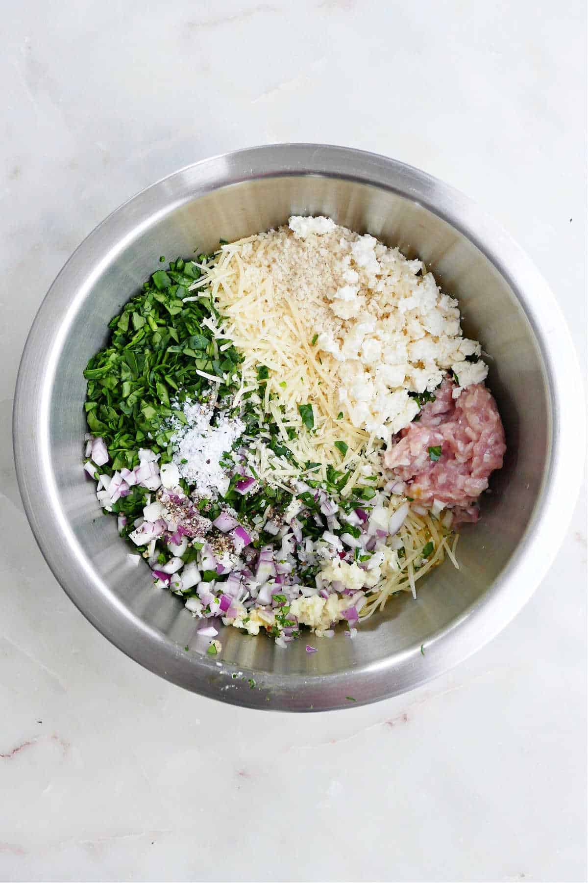 ingredients for spinach chicken meatballs in a mixing bowl on a counter