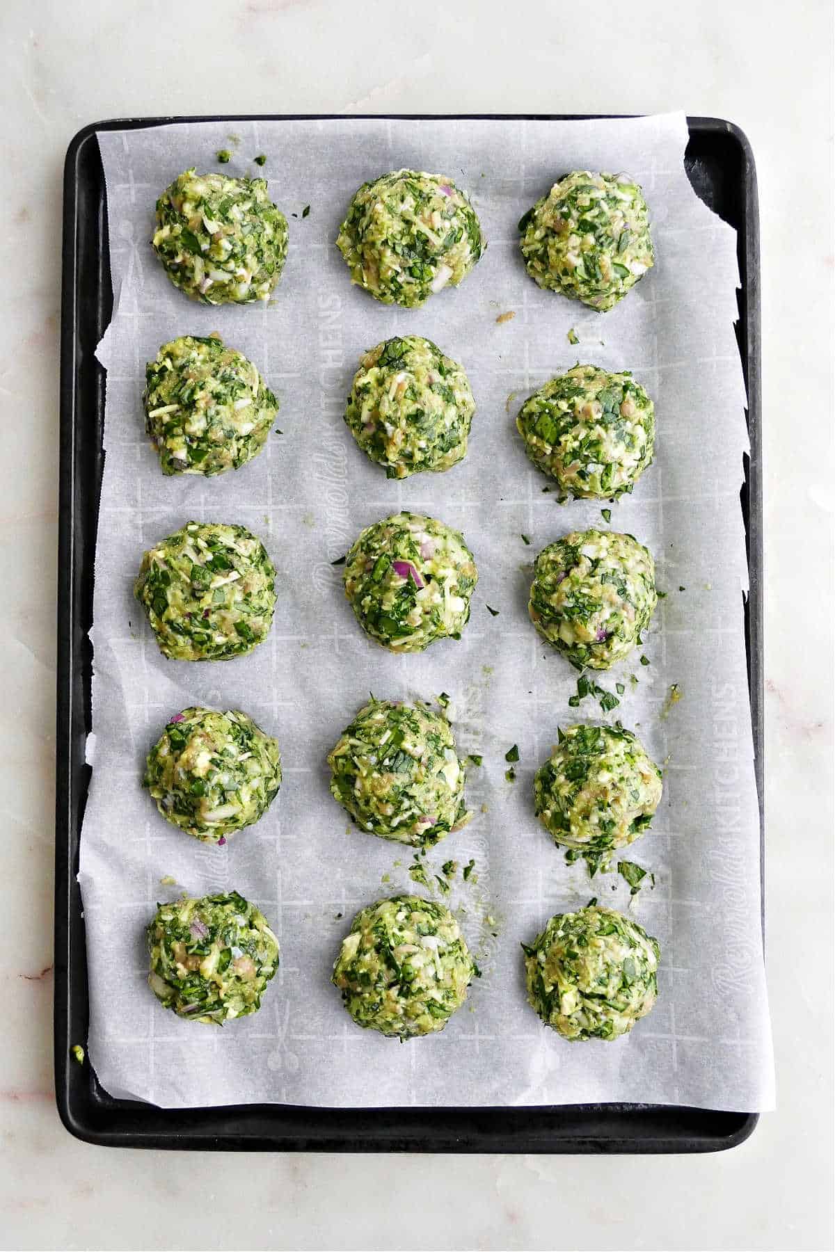 15 spinach chicken meatballs on a baking sheet lined with parchment paper