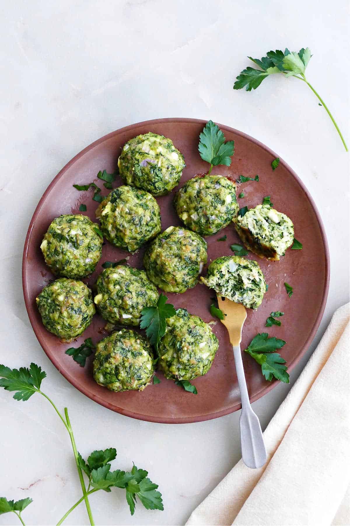 spinach chicken meatballs on a serving plate with a fork in one of them