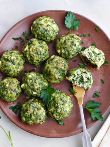 spinach chicken meatballs on a serving plate with a fork in one of them