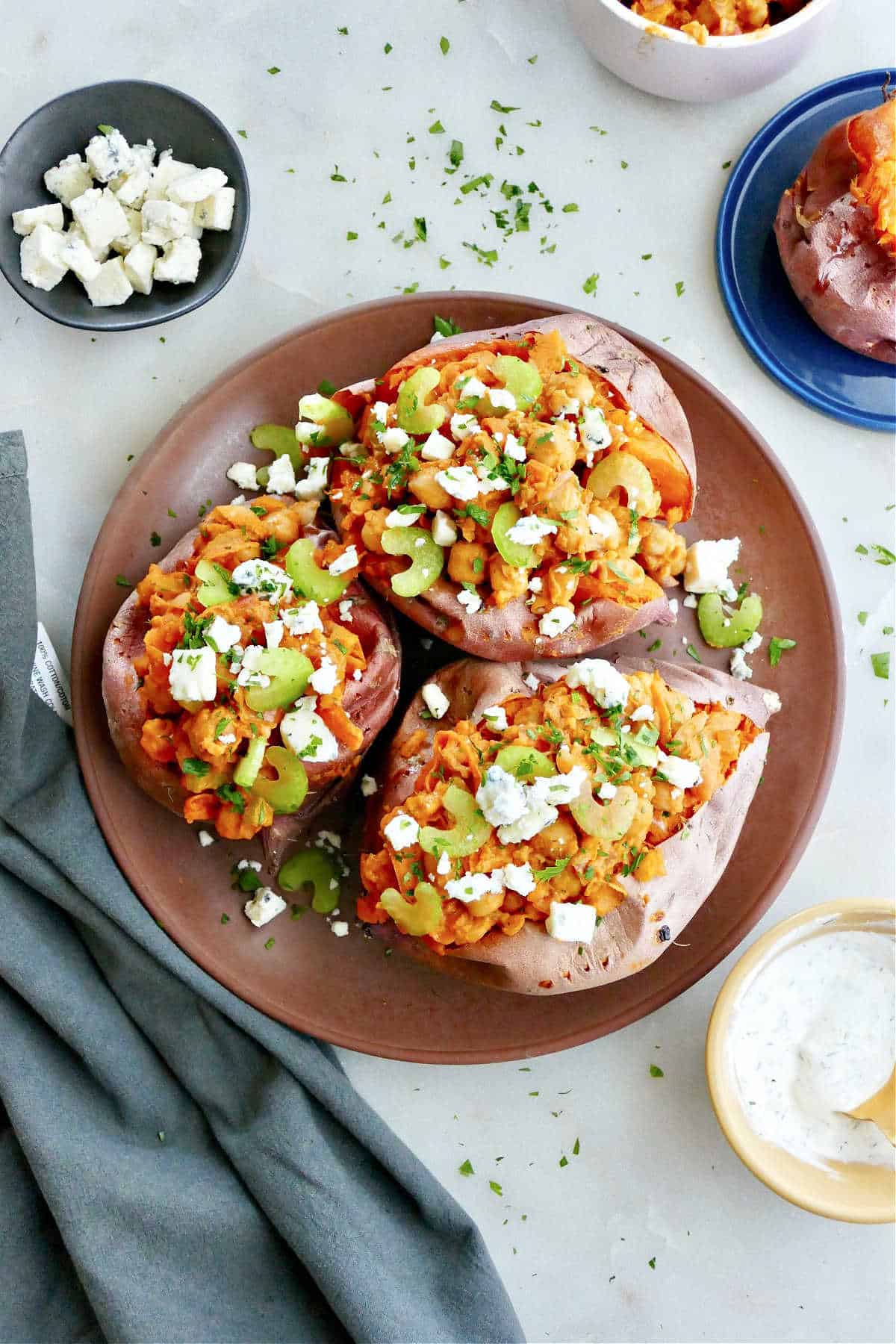 three sweet potatoes stuffed with buffalo chickpeas on a serving plate on a counter
