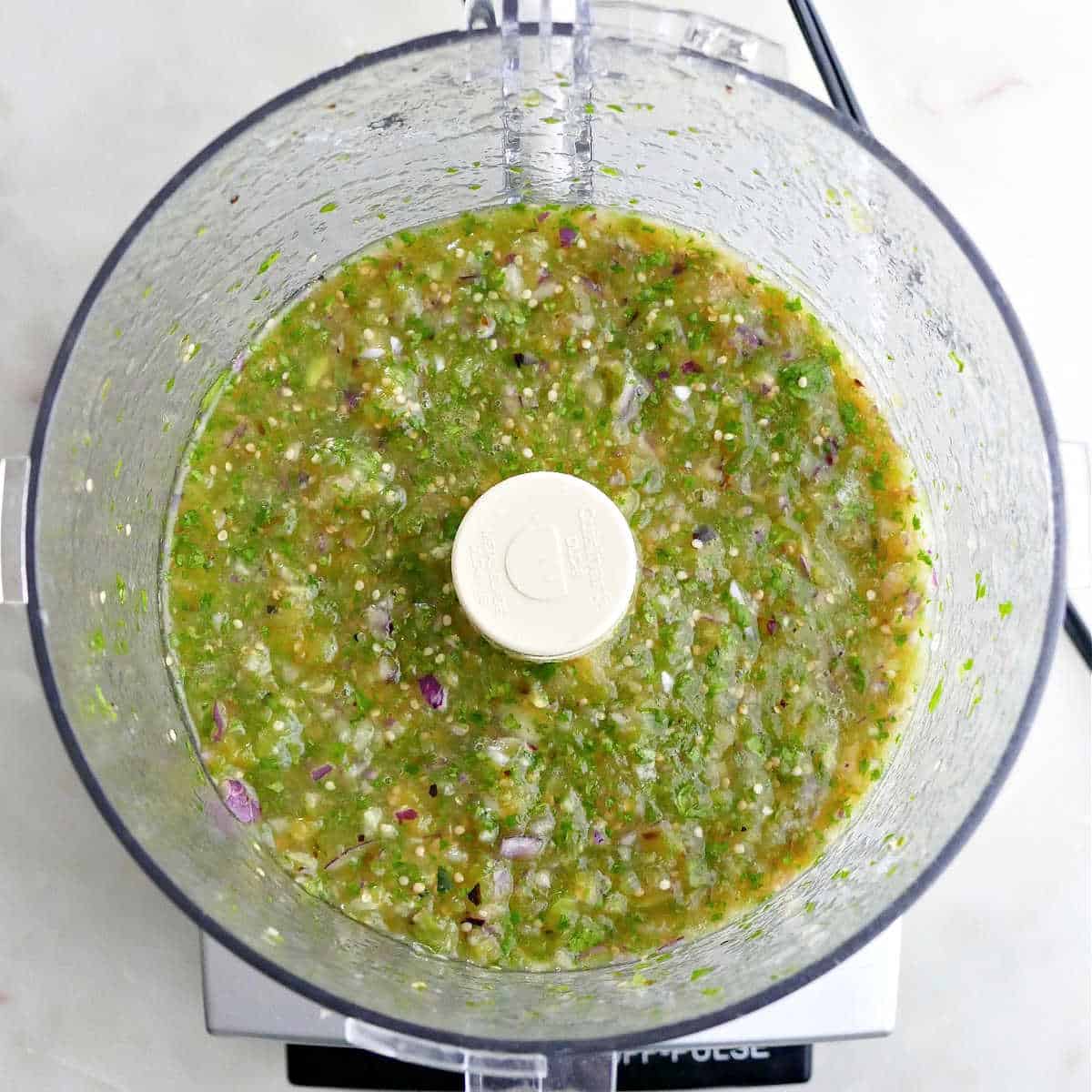 tomatillo green chili salsa mixed in a food processor on top of a counter