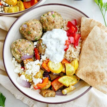 Greek meatball and vegetable bowl with pita triangles on a counter