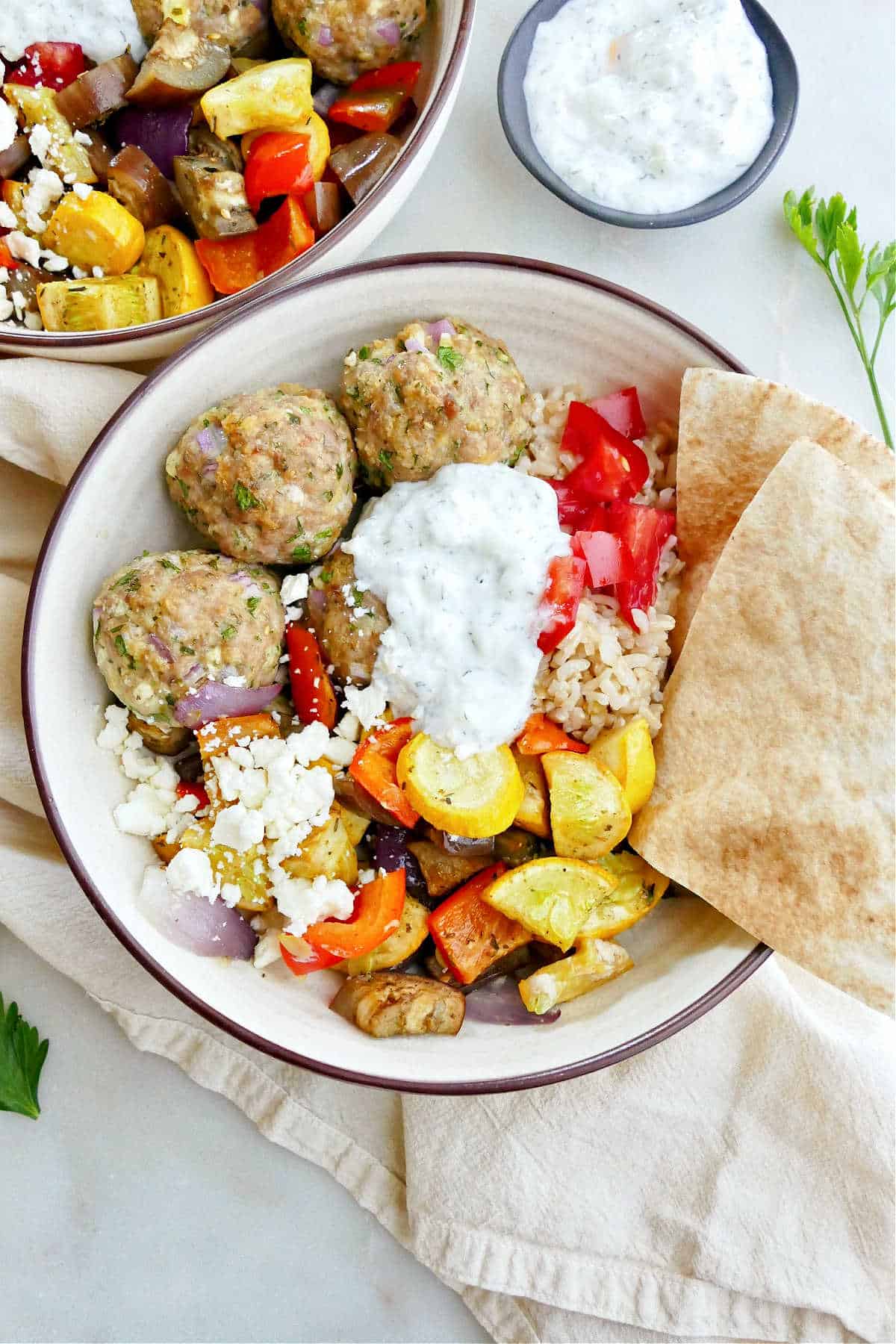 Greek meatball and vegetable bowl with pita triangles on a counter