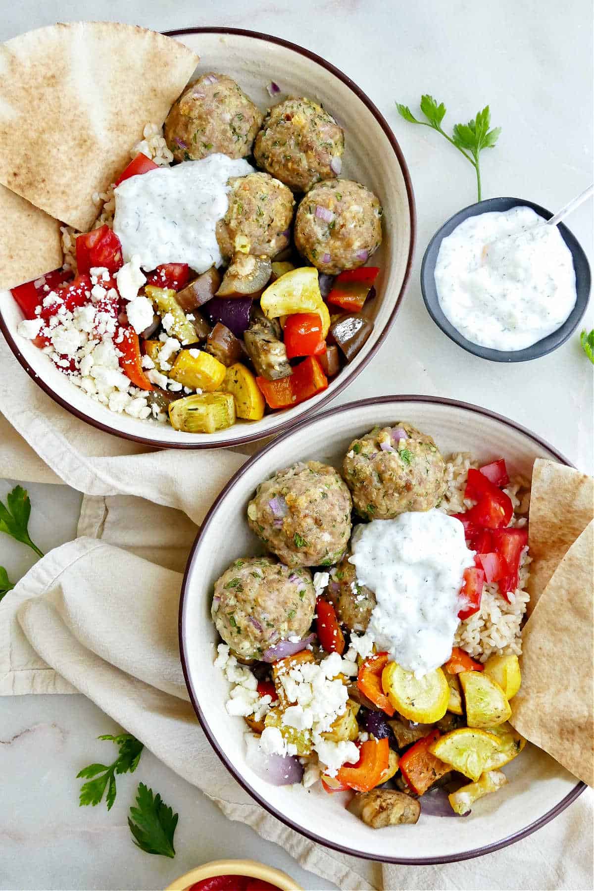 two Greek meatball and veggie bowls next to each other on a counter