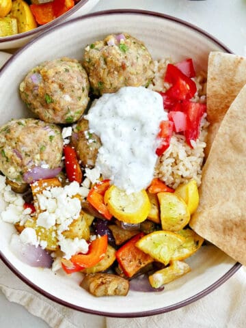 Greek meatball and vegetable bowl with pita triangles on a counter