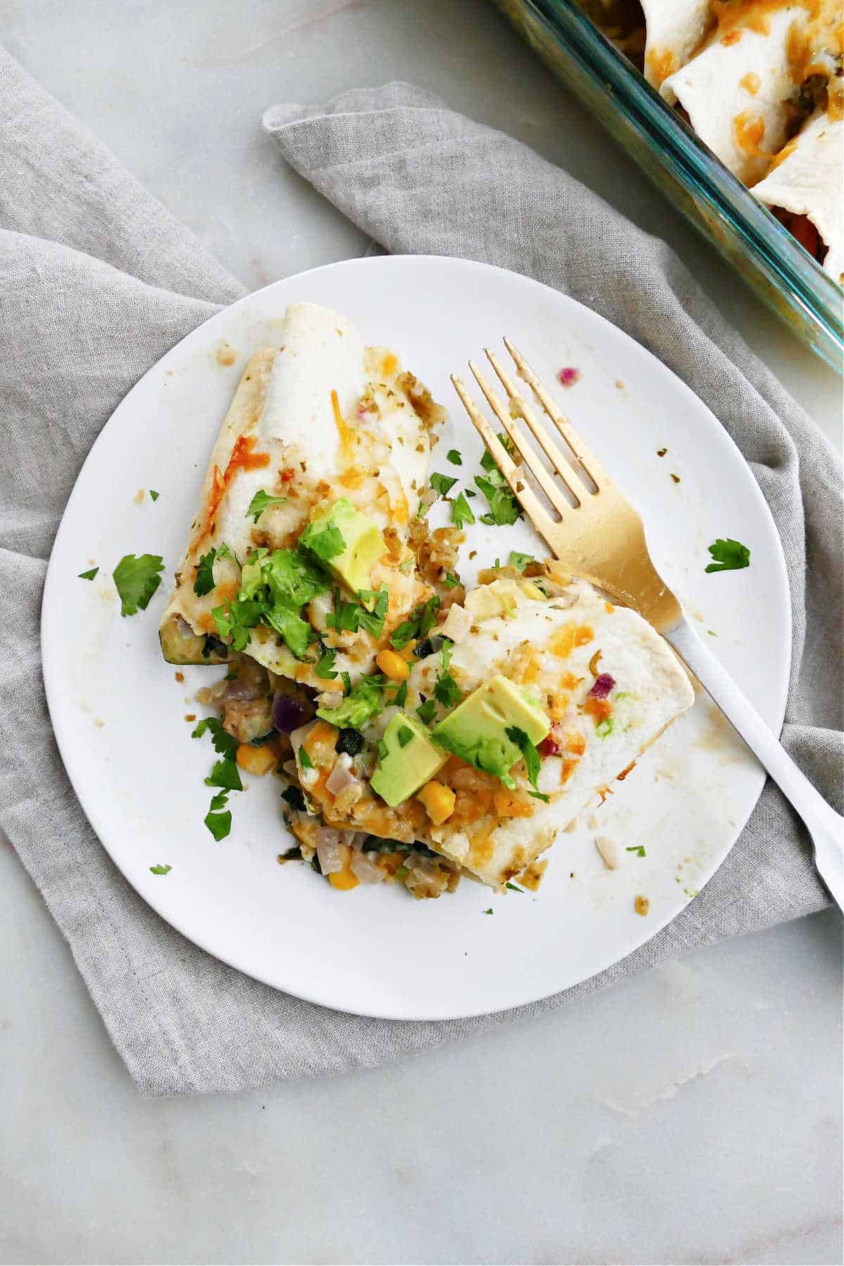an enchilada cut in half with toppings on a plate with a fork